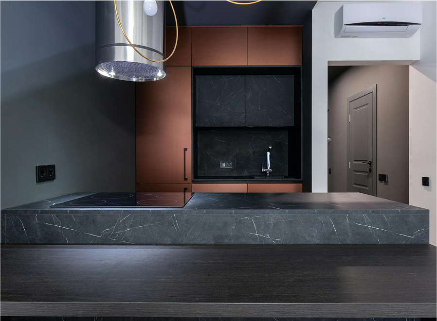 Premium Stones modern kitchen with dark marble countertops and copper cabinetry.
