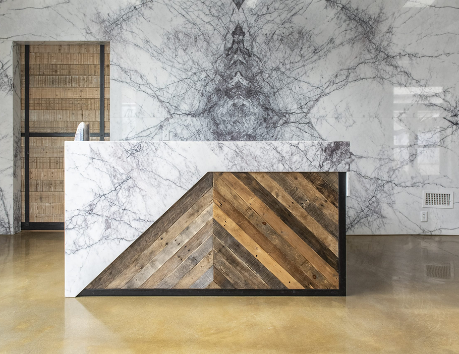 Premium Stones modern reception area featuring a marble-clad counter with a wooden geometric design.