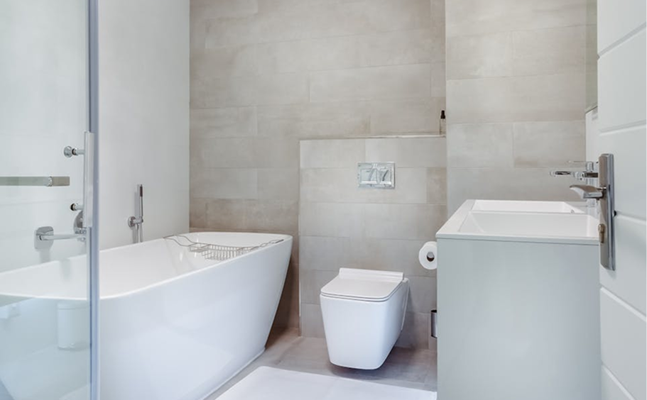 Modern minimalist bathroom with a freestanding bathtub, wall-mounted toilet, and sleek white vanity.