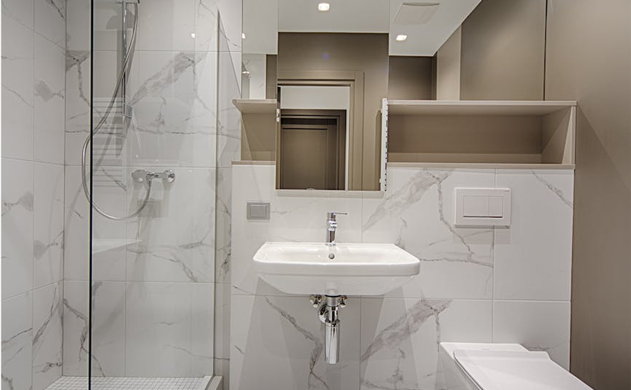 Premium Stones - Modern bathroom with white marble tiles, a sleek wall-mounted sink, and a glass shower enclosure.