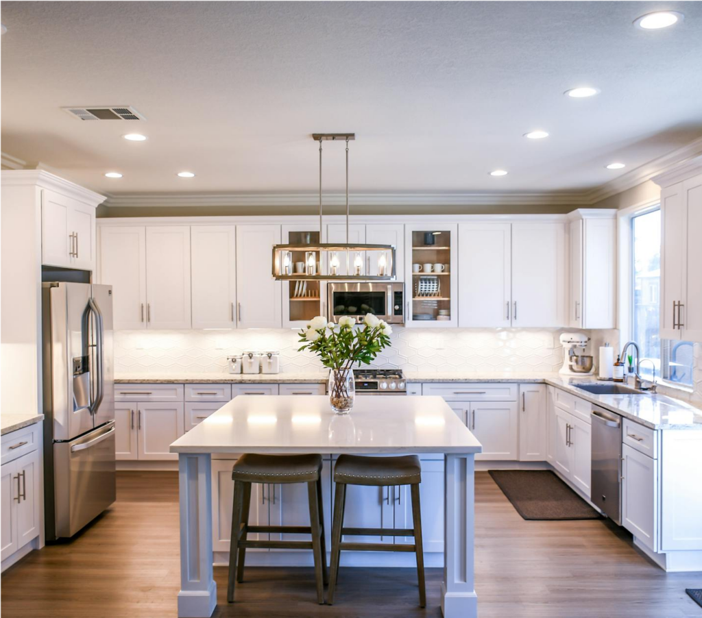 Premium Stones – Modern white kitchen featuring a marble island, sleek cabinetry, and stylish lighting.